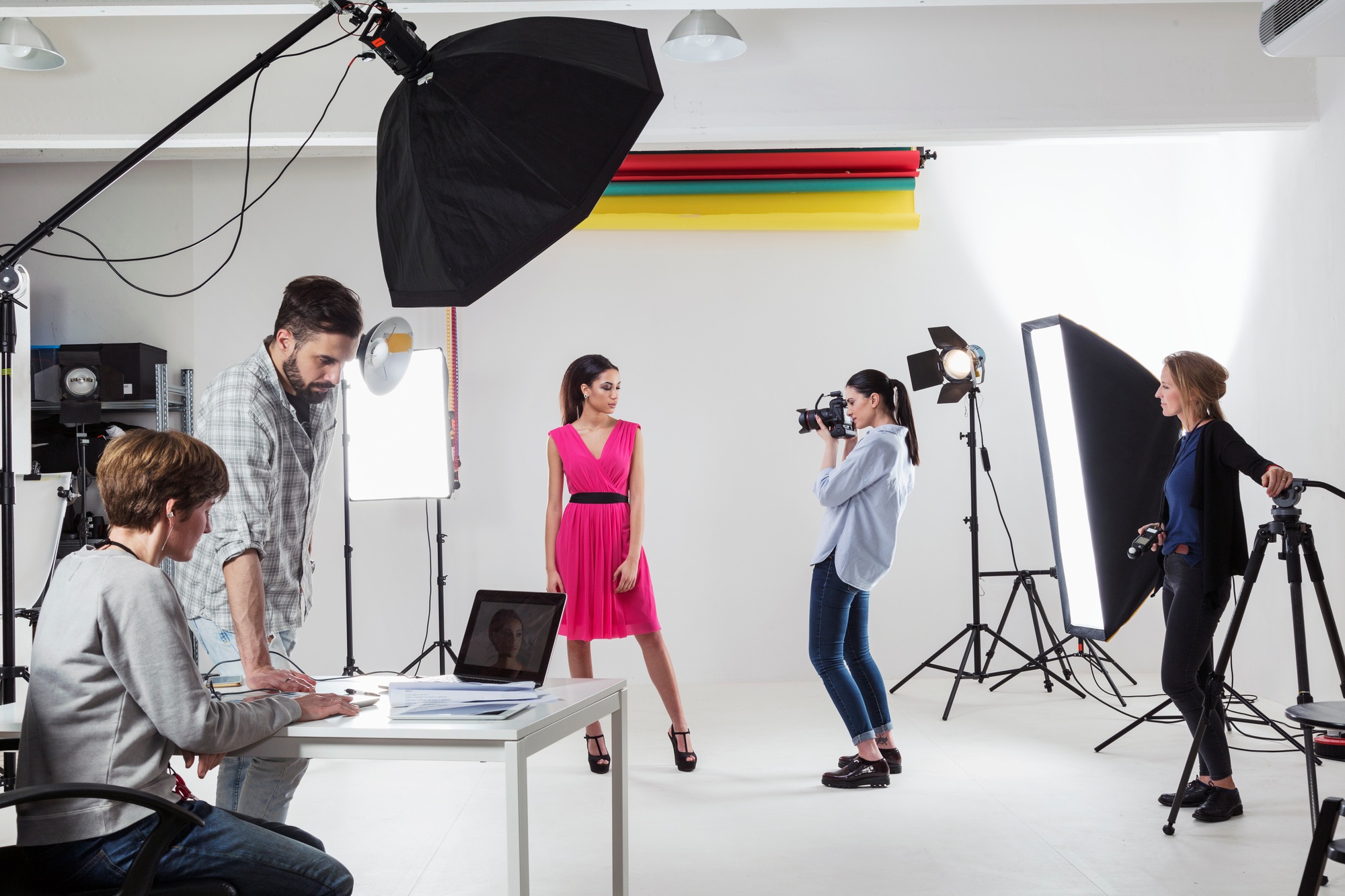 Photographer photographing fashion model in white backdrop photography studio shoot